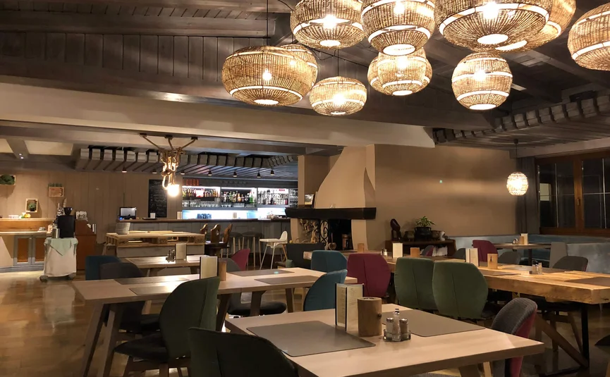 Gemütliches Restaurant mit hölzernen Tischen, bunten Stühlen und dekorativen Lampen