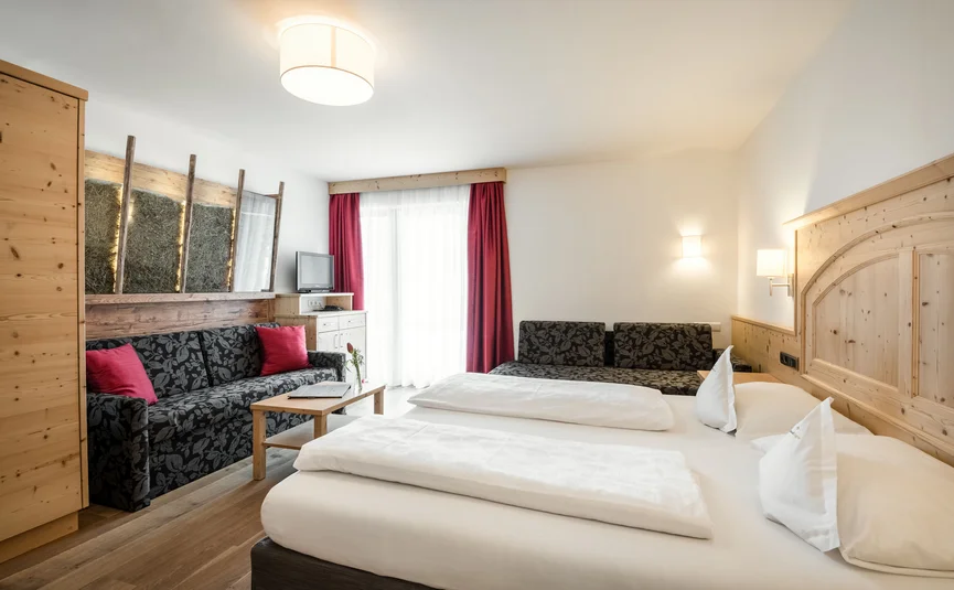 Lichte hotelkamer met tweepersoonsbed, twee banken en houten wandbekleding