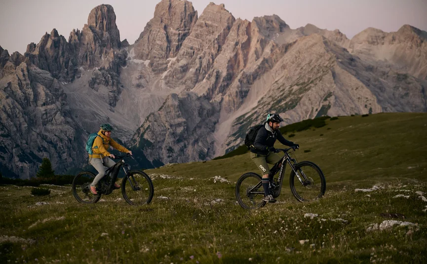 HIRBEN Naturlaub **** © David Rasche Two mountain bikers riding on a grassy field with tall mountains