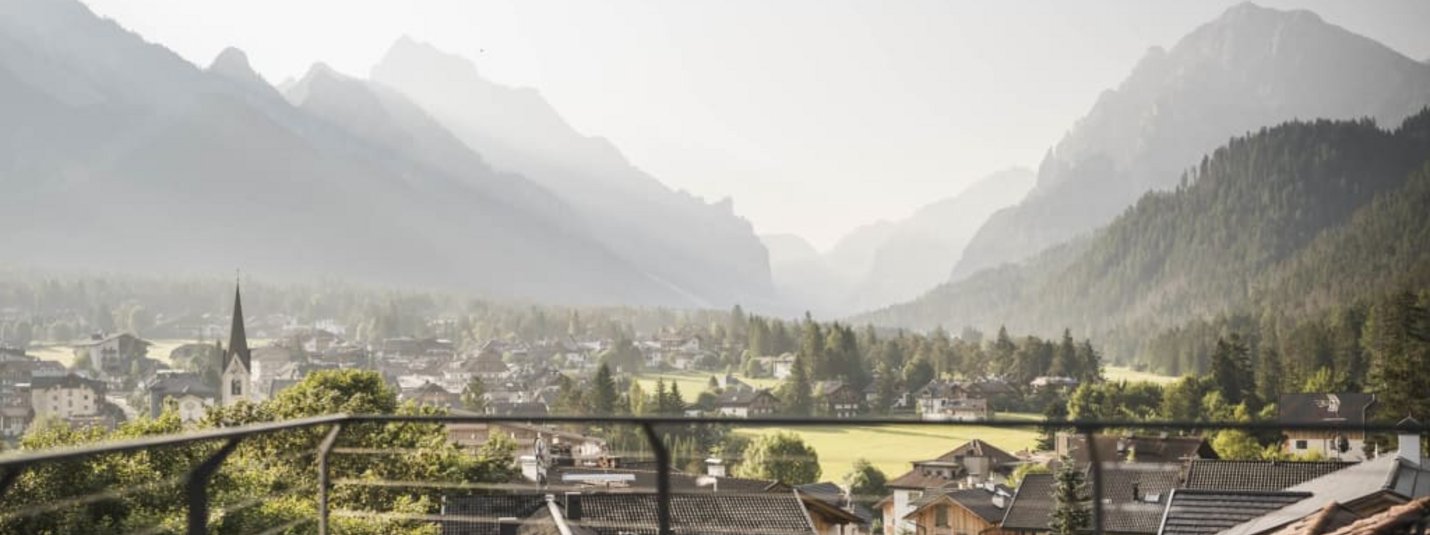 Balcony with chairs and table overlooking a valley with mountains in the background