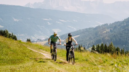 Bike-Region Flachau – von Radabenteuer bis Signature Ride © Flachau Tourismus - Simon Reisinger Zwei Menschen fahren mit Mountainbikes auf einem Bergweg im Grünen