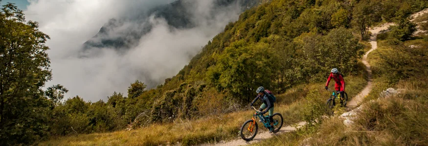 Nördlicher Gardasee © David Karg Zwei Mountainbiker fahren auf einem Bergweg durch nebligen Wald