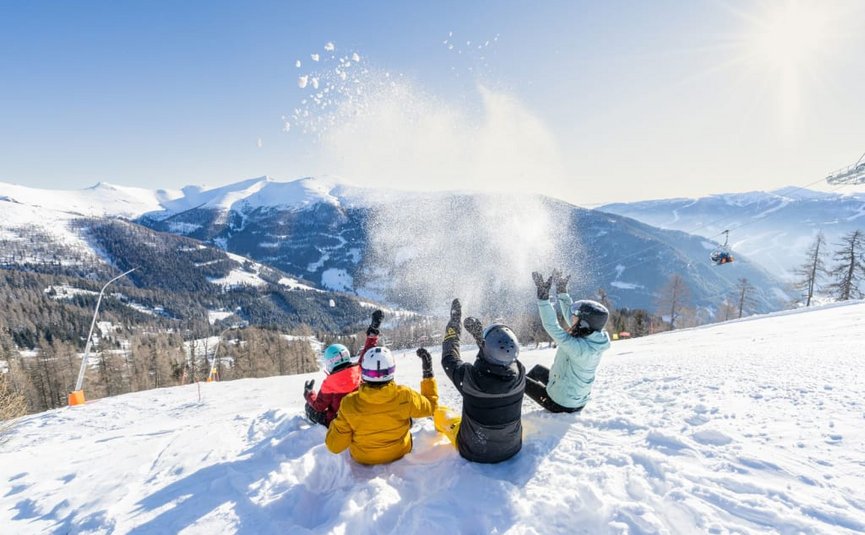 Christkindltage für Dich Vier mensen gooien sneeuw in de lucht op zonnige besneeuwde berg