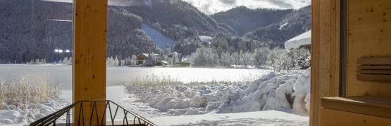 Holzsauna mit Blick auf schneebedeckte Berge und See