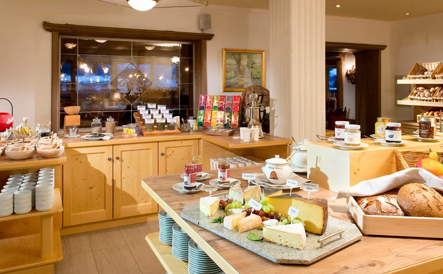 Breakfast buffet with cheese, bread, jam, and fresh fruit in cozy setting