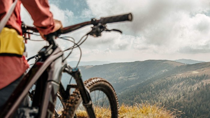 Mountainbiker mit Blick auf bewaldete Berge und bewölkten Himmel