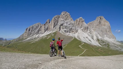 Zwei Radfahrer betrachten die Dolomiten unter klarem blauem Himmel