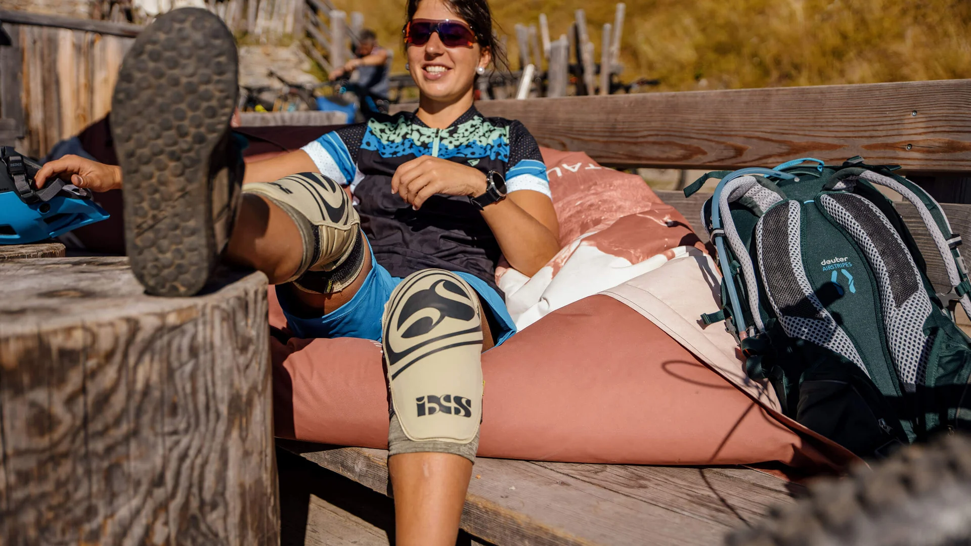 Frau mit Fahrradschutzknieschützern entspannt auf einer Gartenbank