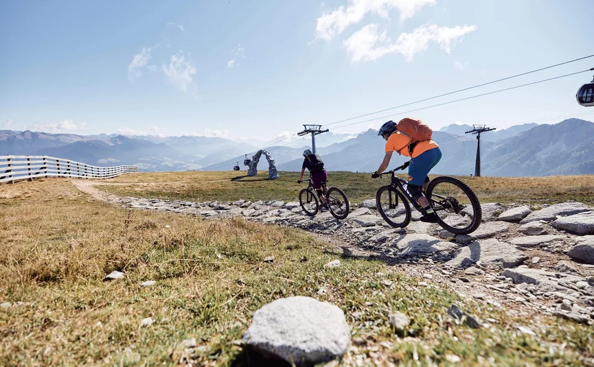 Zwei Mountainbiker fahren auf einem felsigen Bergweg bei Sonnenschein
