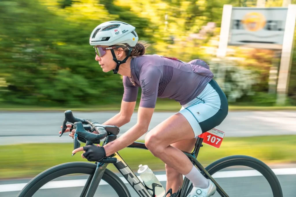 Woman wearing helmet and sunglasses riding road bike outdoors