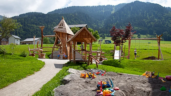 Children's playground with wooden structures and sandbox by mountains