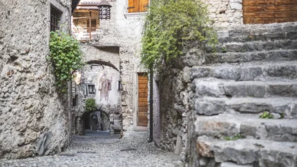 Narrow cobblestone path with stairs and mural in an old village