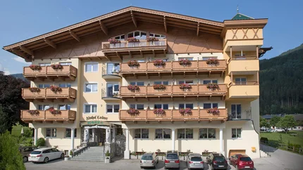 Hotel mit Blumenschmuck an Balkonen und Autos vor dem Eingang