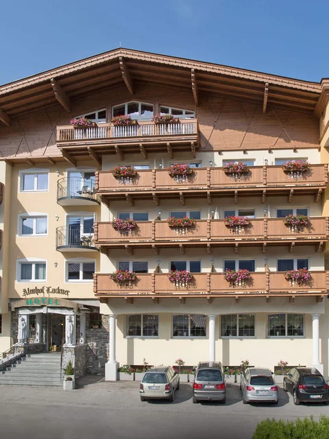 Hotel mit Blumenschmuck an Balkonen und Autos vor dem Eingang