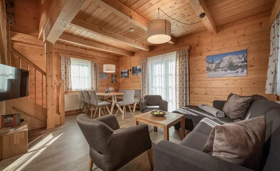 Ski Woche 7 Nächte inkl. Skipass Wohn- und Essbereich eines Chalets mit Holzwänden, Sofa, Sesseln und Esstisch