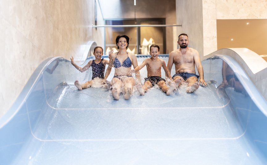 Alpen Hotel Post **** © Alpen Hotel Post - Hof 437 Familie rutscht gemeinsam eine Wasserrutsche hinab im Schwimmbad