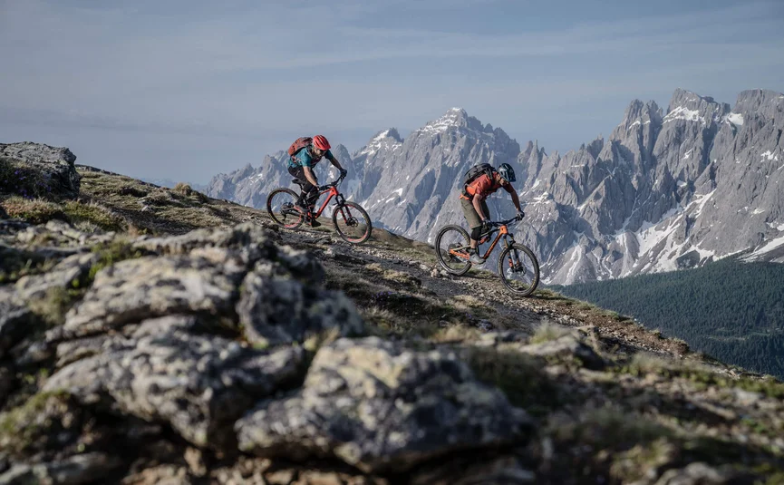 Mountainbike-Urlaub in der Region 3 Zinnen Dolomites © Tourismusverein Sexten - Dennis Stratmann Zwei Mountainbiker fahren auf einem Bergpfad mit Alpen im Hintergrund