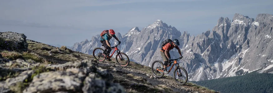 3 Zinnen Dolomites © Tourismusverein Sexten - Dennis Stratmann Zwei Mountainbiker fahren auf einem Bergpfad mit Alpen im Hintergrund