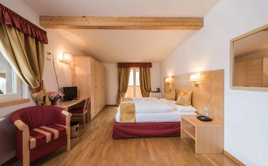 Helles Hotelzimmer mit Doppelbett, Sessel, Schreibtisch und Balkon