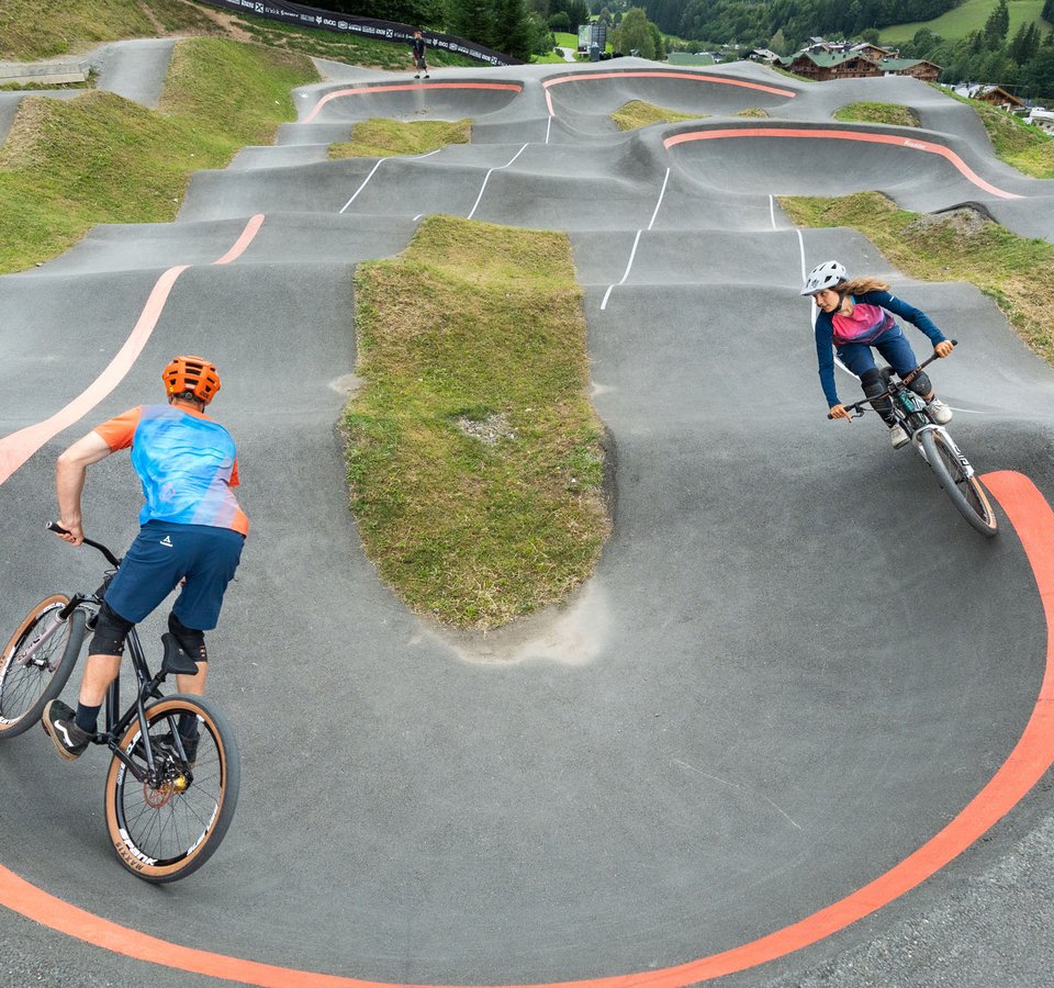 Two cyclists riding on a curvy outdoor BMX track