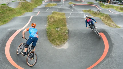 Zwei Radfahrer fahren auf einem kurvigen BMX-Parcours im Freien