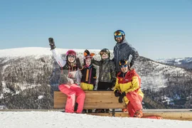 Group of skiers posing on snowy mountain under clear blue sky
