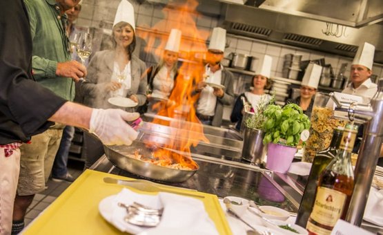 SKI+WINE DAYS Kok flambeert eten voor groep met kokshelmen in keuken