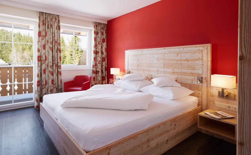 Moderne slaapkamer met bed, rode muren en uitzicht buiten