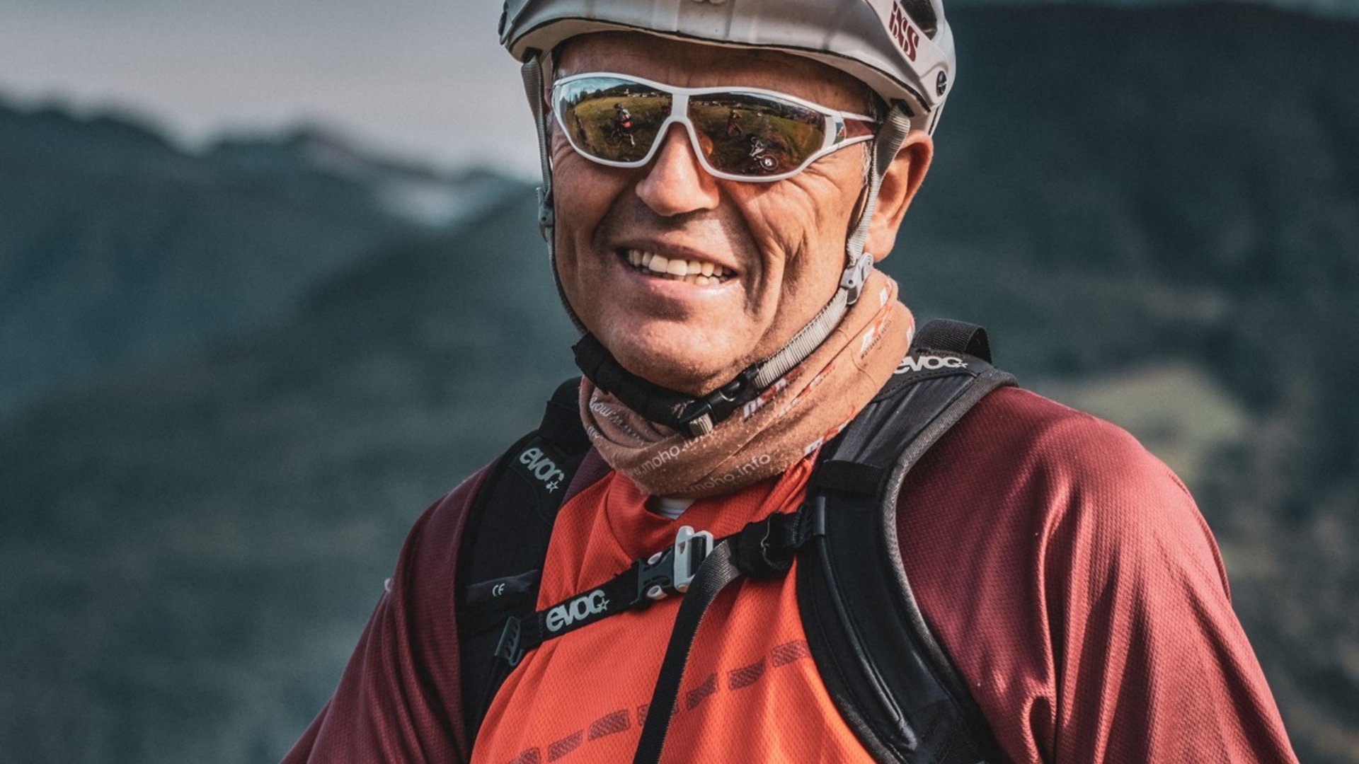 Älterer Mann mit Fahrradhelm und Sonnenbrille in Outdoor-Bekleidung