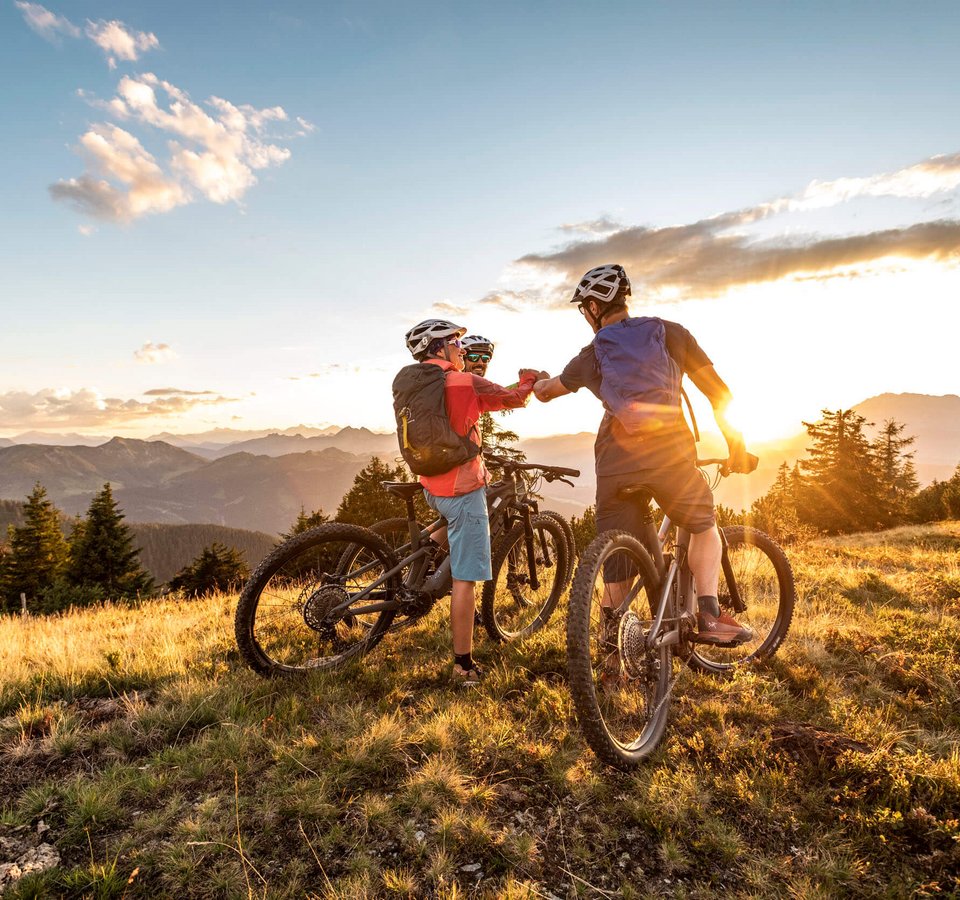 Zwei Mountainbiker grüßen sich bei Sonnenuntergang in den Bergen
