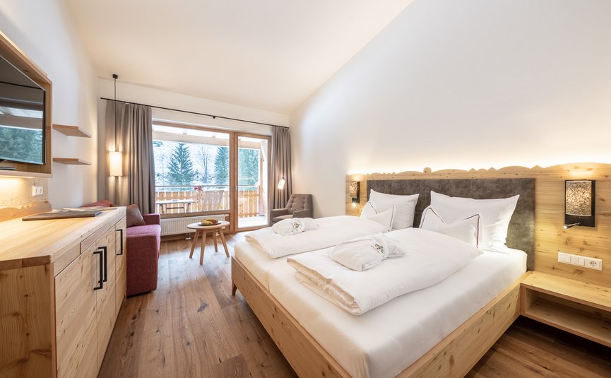 Lichte slaapkamer met tweepersoonsbed, balkon en houten decoratie