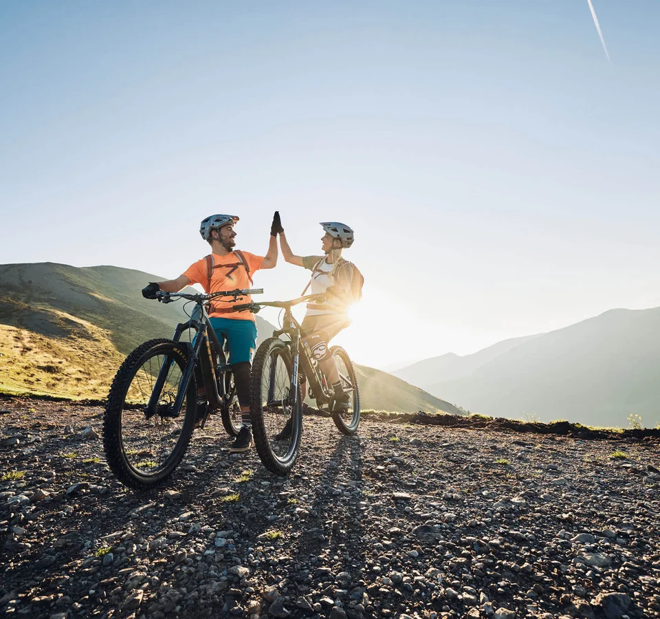 Die besten Touren & Trails der Alpen © Tobias Köhler Zwei Radfahrer geben sich beim Mountainbiken in den Bergen einen Highfive