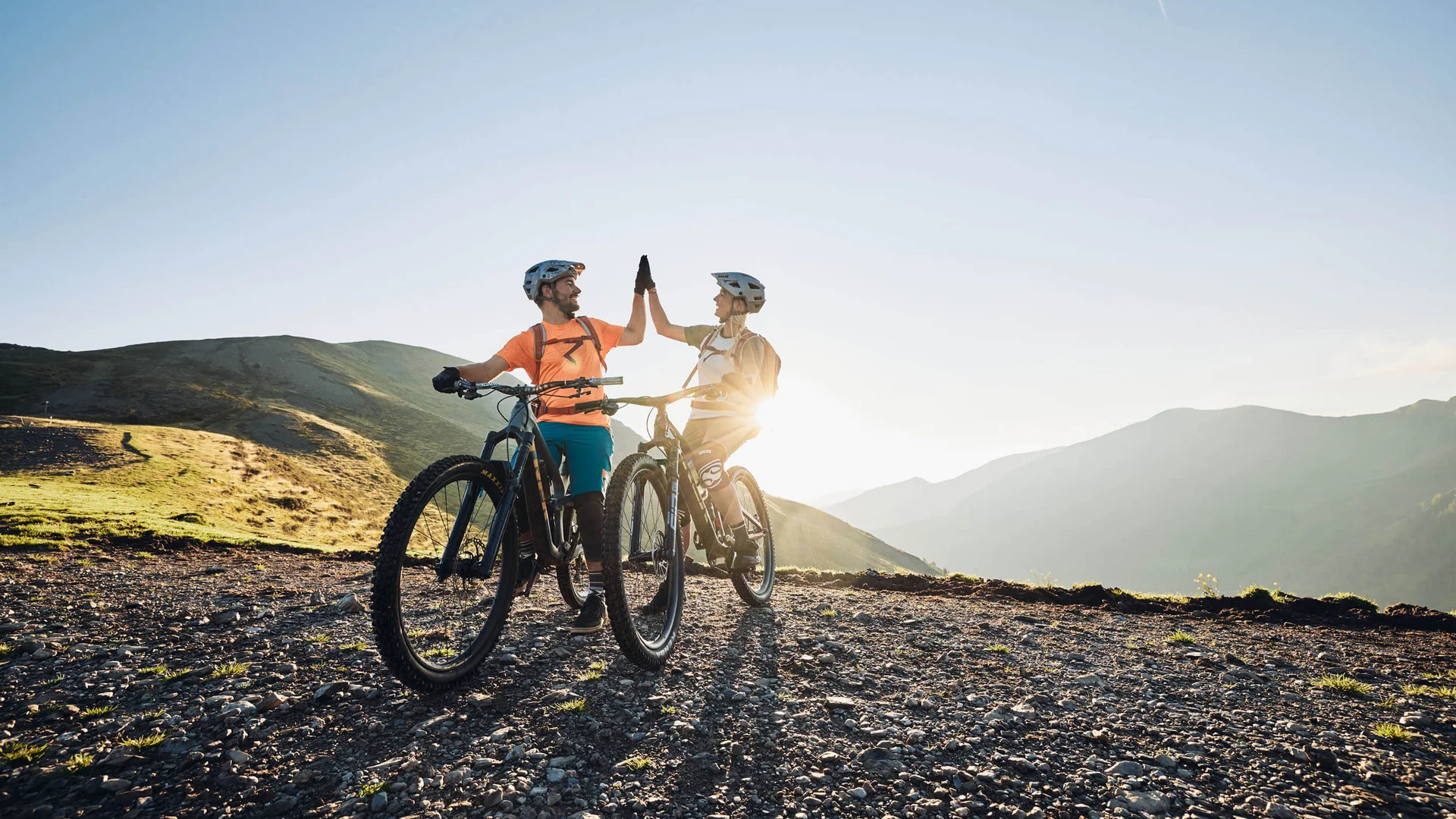 Zwei Radfahrer geben sich beim Mountainbiken in den Bergen einen Highfive
