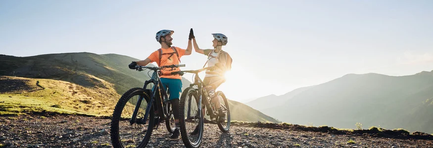 Zwei Radfahrer geben sich beim Mountainbiken in den Bergen einen Highfive