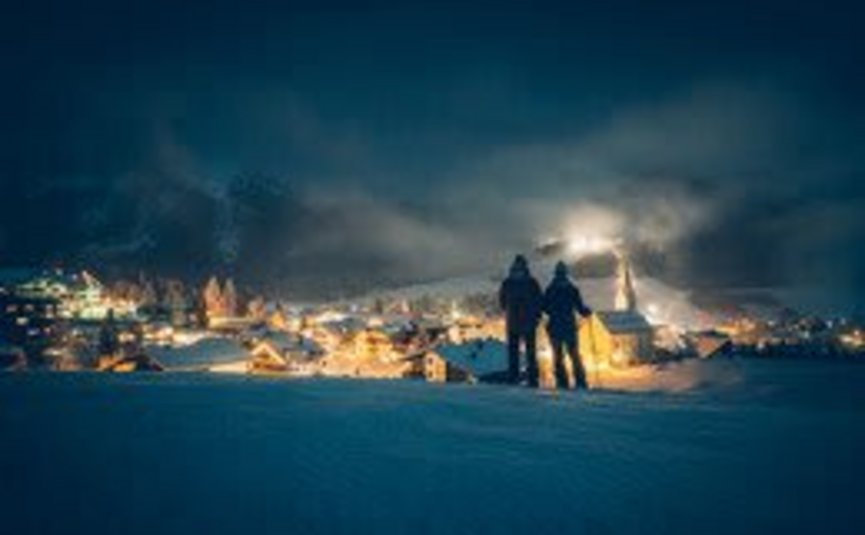 4 day relax-enjoy-skiing on the sunny side of the Zugspitze Two people overlooking a lit village at night in winter