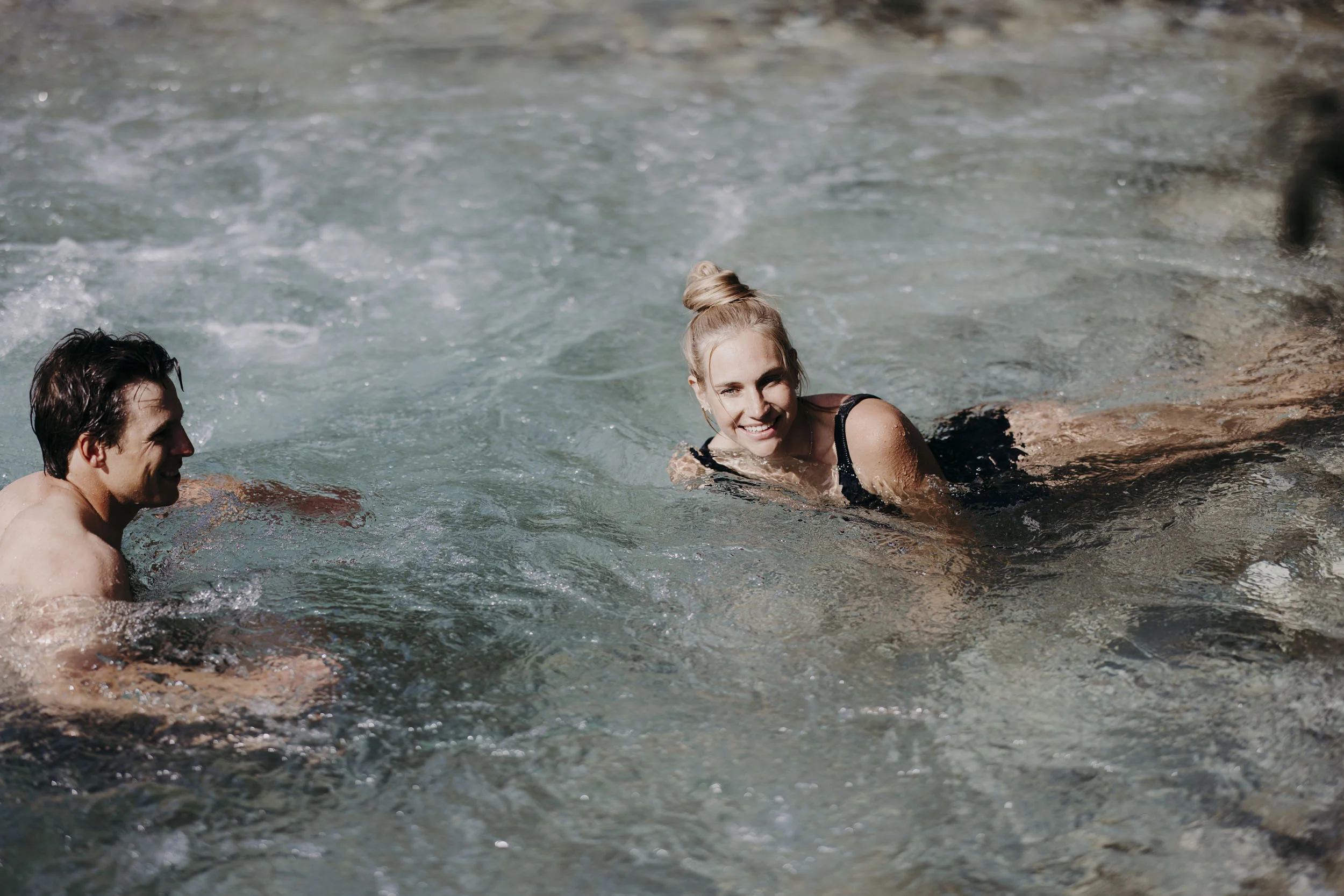 Was steckt hinter dem Umweltengagement von Bikehotels? Mann und Frau entspannen in einem natürlichen Whirlpool mit sprudelndem Wasser