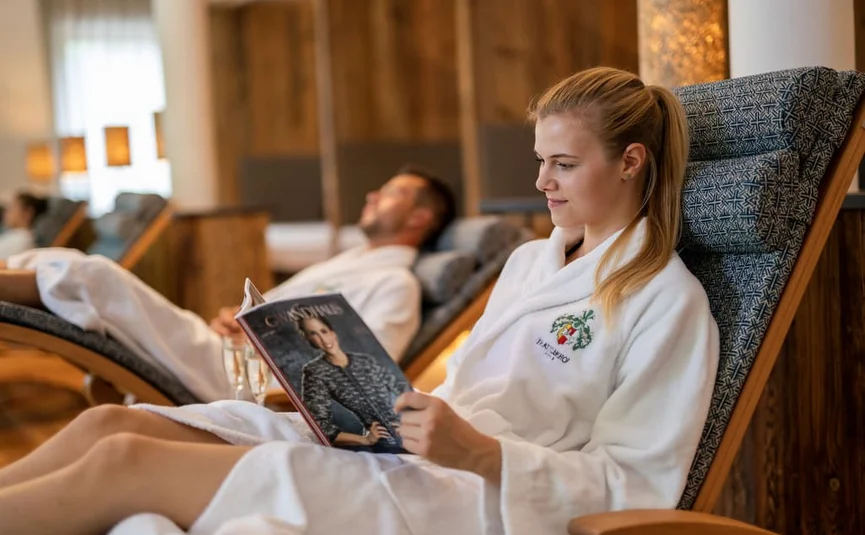 Woman in bathrobe reading magazine in a spa relaxation area