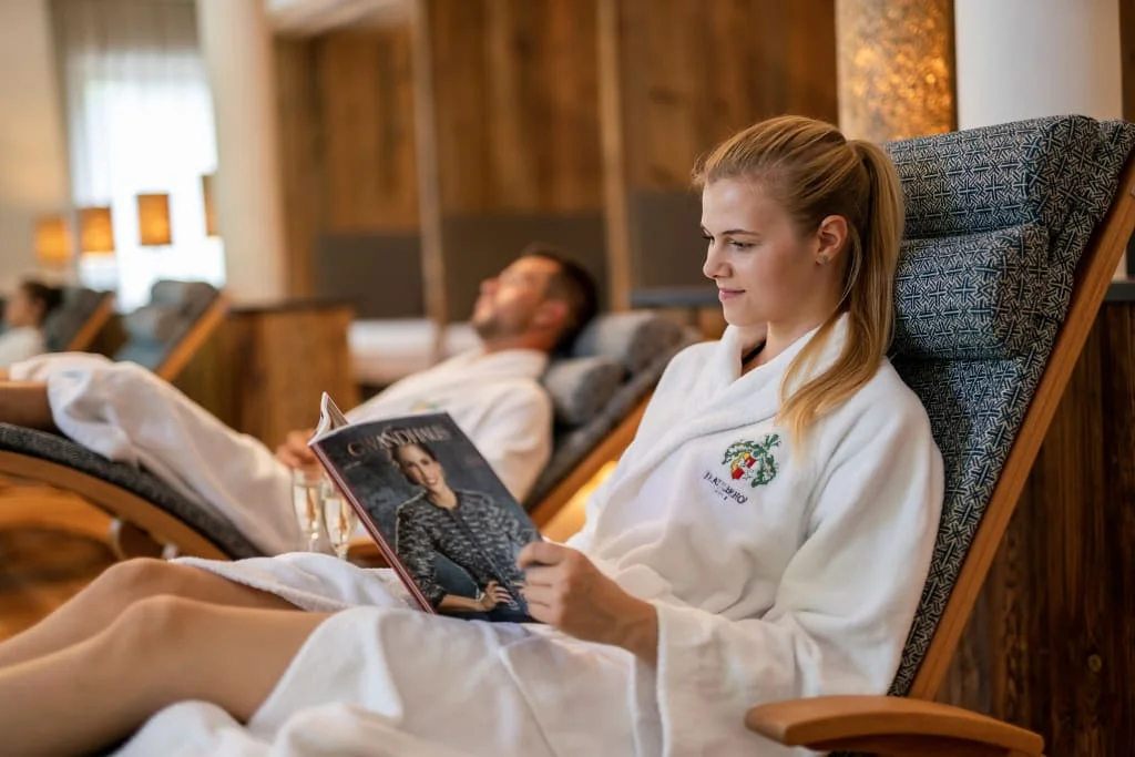 Woman in bathrobe reading magazine in a spa relaxation area