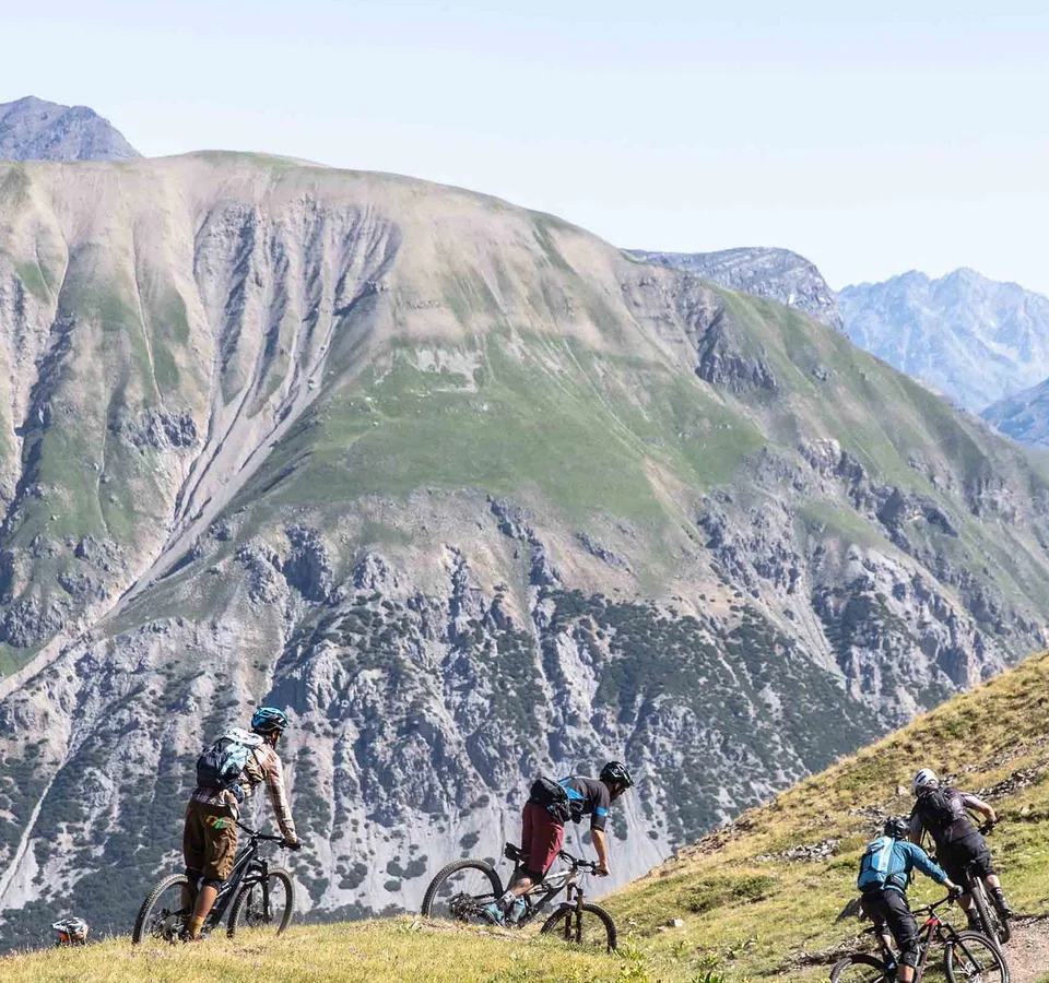 Gruppe Mountainbiker fährt auf Bergpfad mit Alpen im Hintergrund
