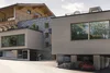 Modernes Hotel mit Kombination aus Holz- und Stein Fassade und rotem Auto vor der Garage