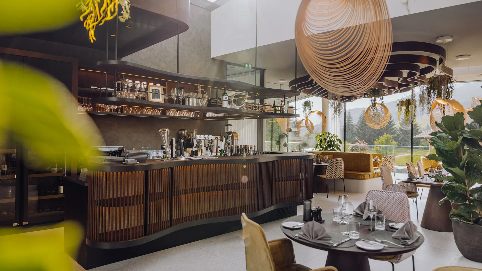 Modernes Restaurant mit Bar, dekorativen Lampen und Panoramafenstern mit Waldblick
