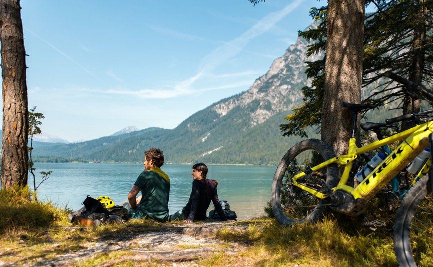 Mountainbikevakantie in de Tiroler Zugspitz Arena © David Karg Twee fietsers zitten aan het meer met bergen op de achtergrond