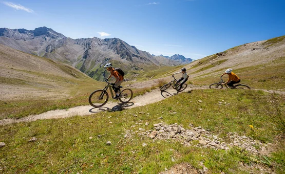 Drei Mountainbiker fahren einen Bergpfad in den Alpen bei sonnigem Wetter