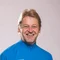 Lächelnder Mann in blauem Mountain Bike Trikot vor neutralem Hintergrund