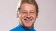 Lächelnder Mann in blauem Mountain Bike Trikot vor neutralem Hintergrund