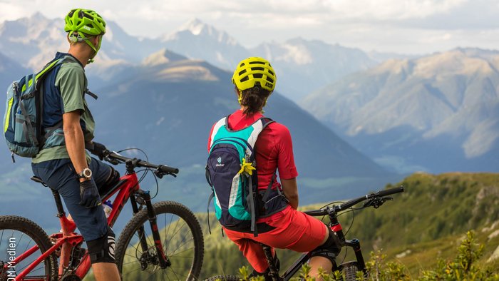 Mountainbike-Saisonstart am Kronplatz © WOM Medien - Andreas Meyer Zwei Mountainbiker mit Helmen stehen auf Bergpfad mit Alpenpanorama