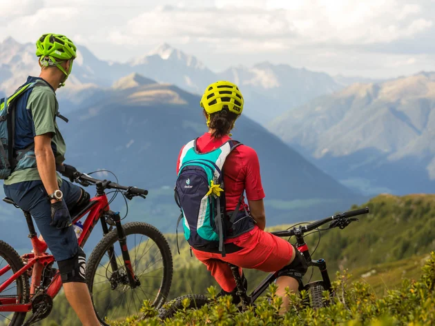Ein perfekter Enduro-Tag – vom ersten Höhenmeter bis zum letzten Trail © WOM Medien - Andreas Meyer Zwei Mountainbiker mit Helmen stehen auf Bergpfad mit Alpenpanorama