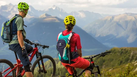 Ein perfekter Enduro-Tag – vom ersten Höhenmeter bis zum letzten Trail © WOM Medien - Andreas Meyer Zwei Mountainbiker mit Helmen stehen auf Bergpfad mit Alpenpanorama