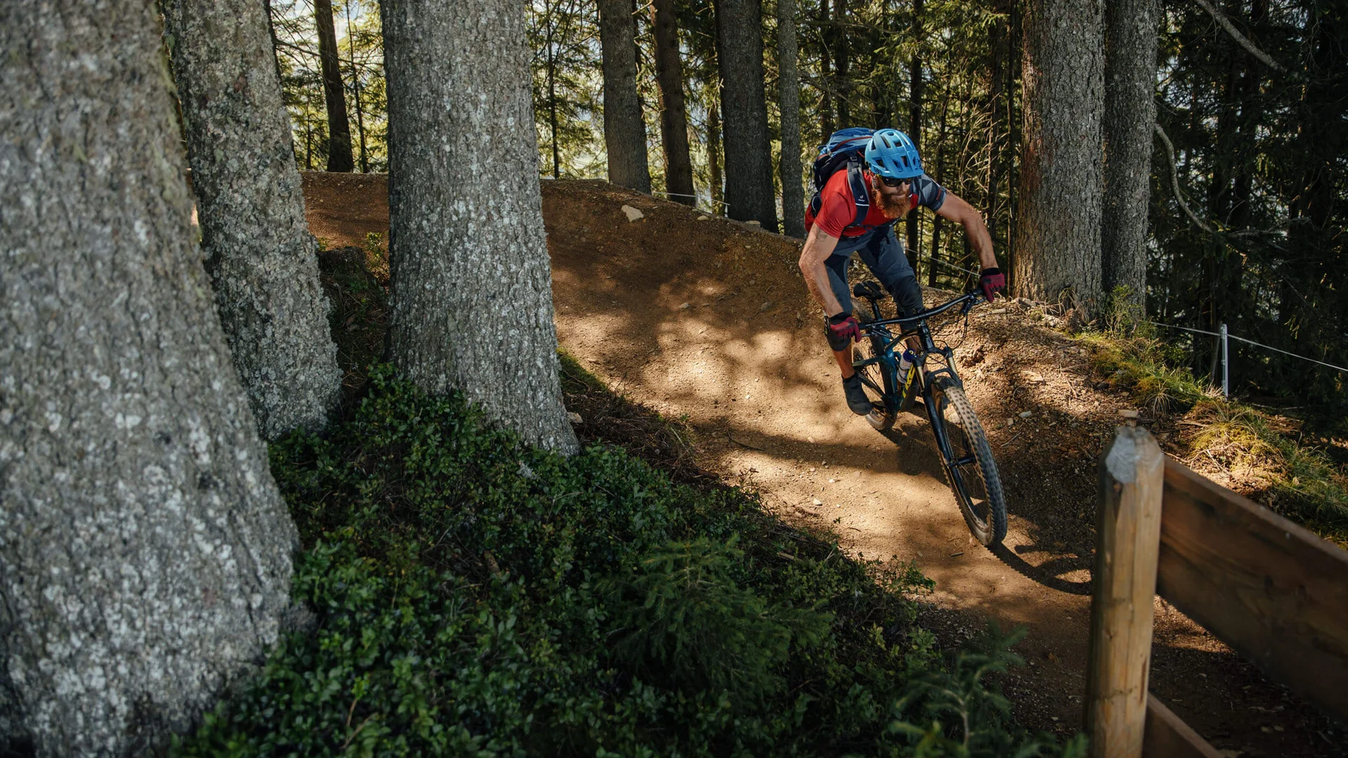 Man mountain biking on forest trail wearing helmet and backpack