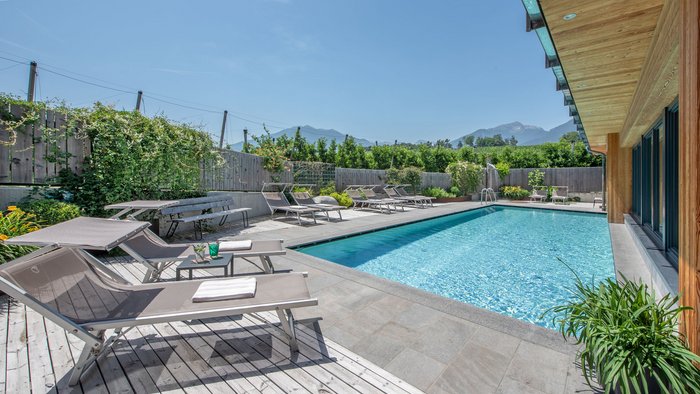 Outdoor-Pool mit Liegestühlen und Bergblick unter klarem Himmel